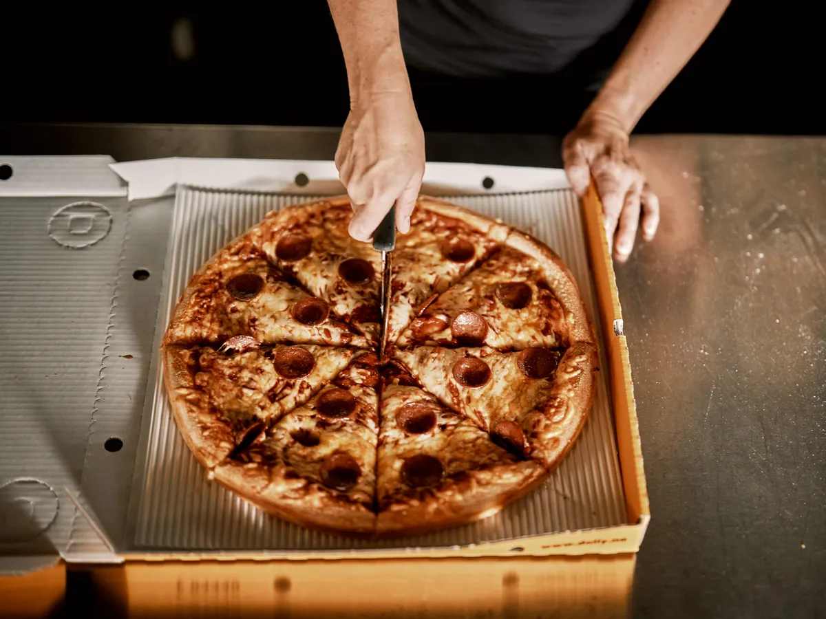 En pepperonipizza blir delt i stykker i en Dolly-eske