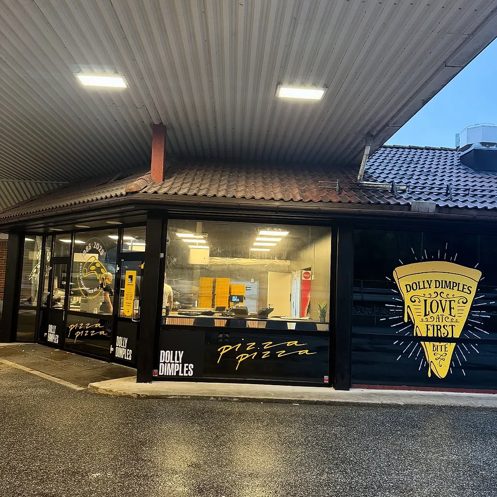 En Dolly Dimples-butikk med et gult «Love at first bite»-pizzastykke på vinduet